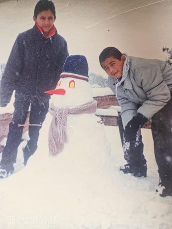 Hermanos laguneros con un mono de nieve durante la nevada en Torreón, 1997