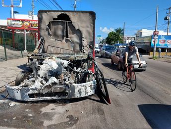 Ciclista transita junto a un vehículo consumido por las llamas un día después del Culiacanazo / Agencia Cuartoscuro