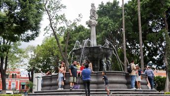 Familias y turistas se toman fotografías en la fuente de San Miguel en el Zócalo de Puebla | Agencia Es Imagen