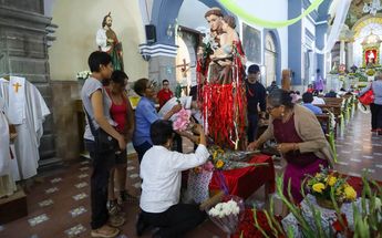 Personas adornan la imagen de San Antonio de Padua antes de salir en procesión en el Centro Histórico de Puebla | Es Imagen