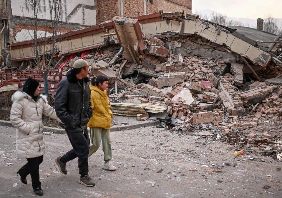 La gente pasa junto a un edificio derrumbado después de un terremoto en China / AFP