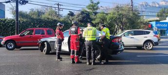 Rescatistas y policías rondeando al motociclista quien está sentado en una patrulla. | Francisco Zúñiga Esquivel
