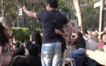 Hombre usando escalera para poder disfrutar del Desfile de Día de Muertos CdMx / Captura