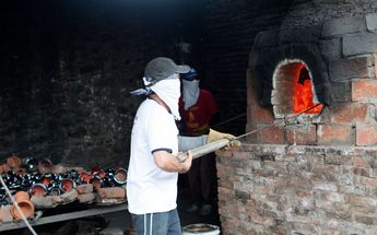 Un alfarero manipula las artesanías de barro dentro de un horno / Andrés Lobato