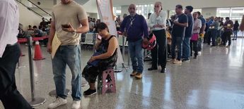 Una mujer mayor formada en la fila con un banquito. | Francisco Zúñiga Esquivel