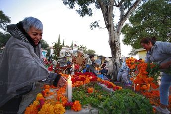 Un par de mujeres sonríen mientras decoran una de las tumbas en la Mixteca poblana / Andrés Lobato