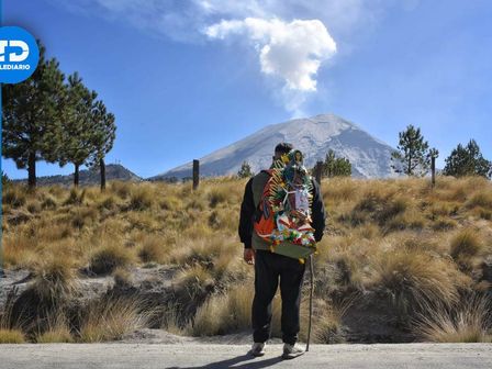 Un peregrino cargando la imagen de la Virgen de Guadalupe en el Paso de Cortés, con el Popocatépetl al fondo | Es Imagen